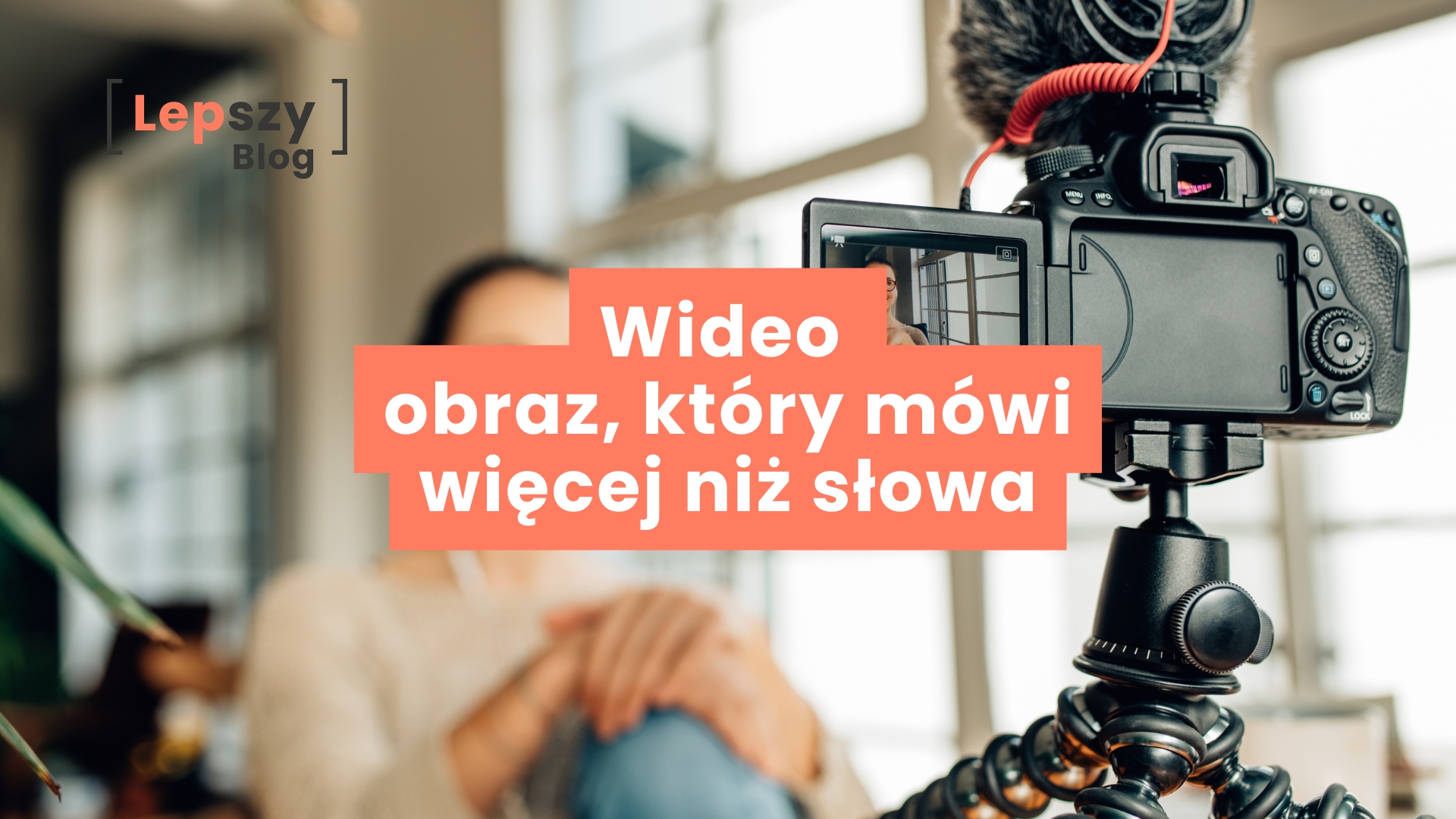 Aparat ustawiony na pierwszym planie nagrywa osobę mówiącą do kamery, wyraźnie widoczną na ekraniku urządzenia, podczas gdy jej sylwetka w tle pozostaje rozmyta – napis „Wideo – obraz, który mówi więcej niż słowa”, symbol mocy wizualnej opowieści i przekazu budowanego kadrem.